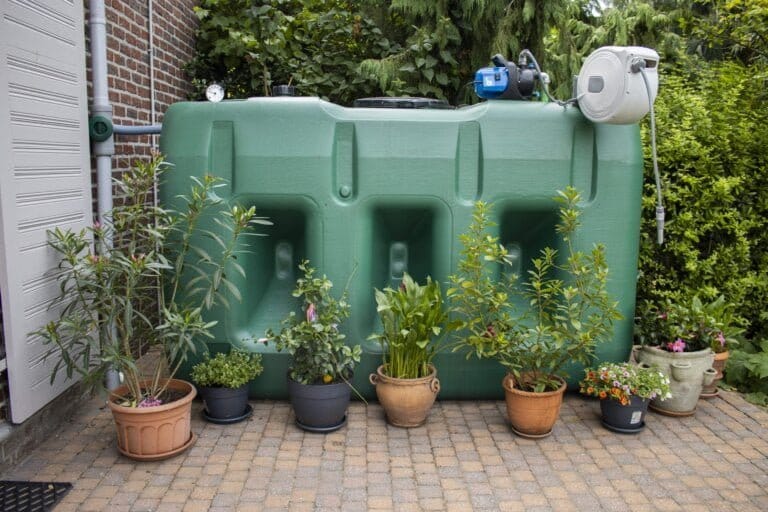 Bovengrondse Watertank 3000 liter met pomp in de tuin naast de bloemen